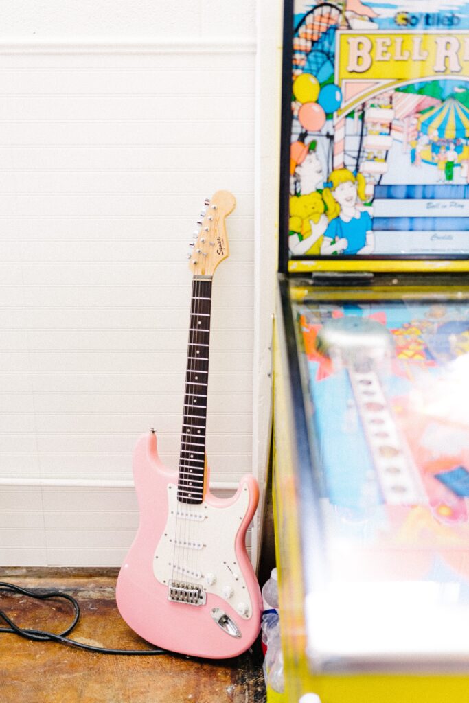 カラフルな絵とその横に立てかけられているピンクのエレキギター