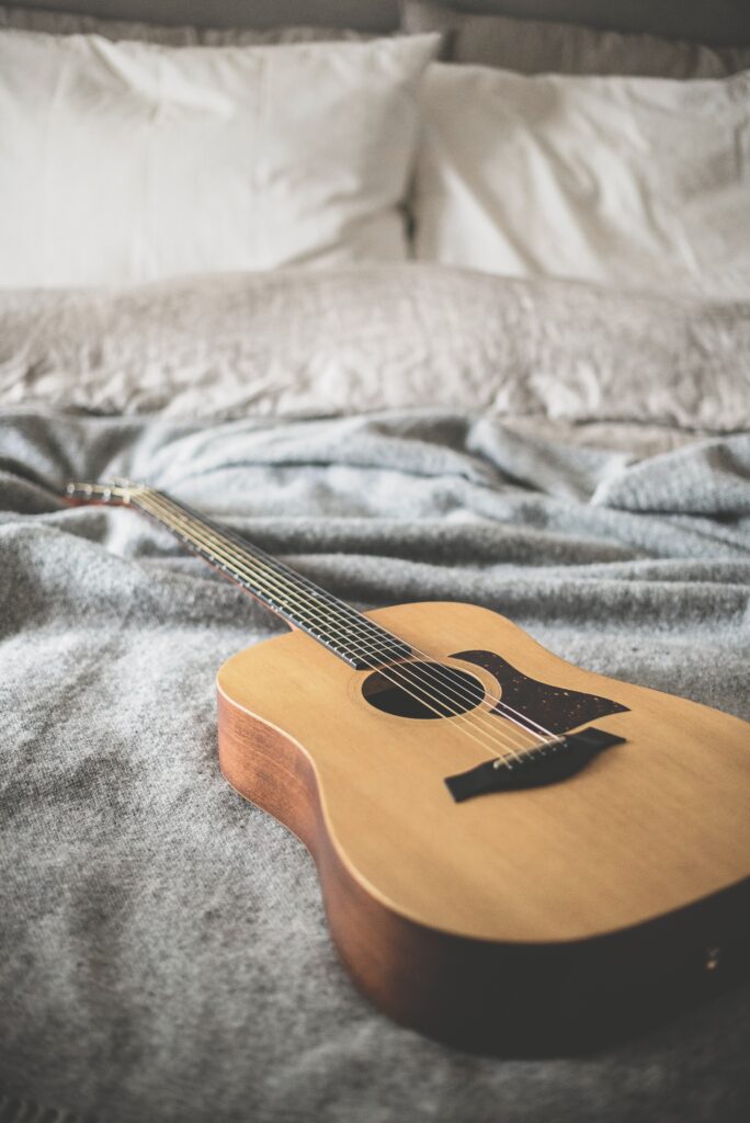 ベッドの上に置いてあるアコースティックギター 