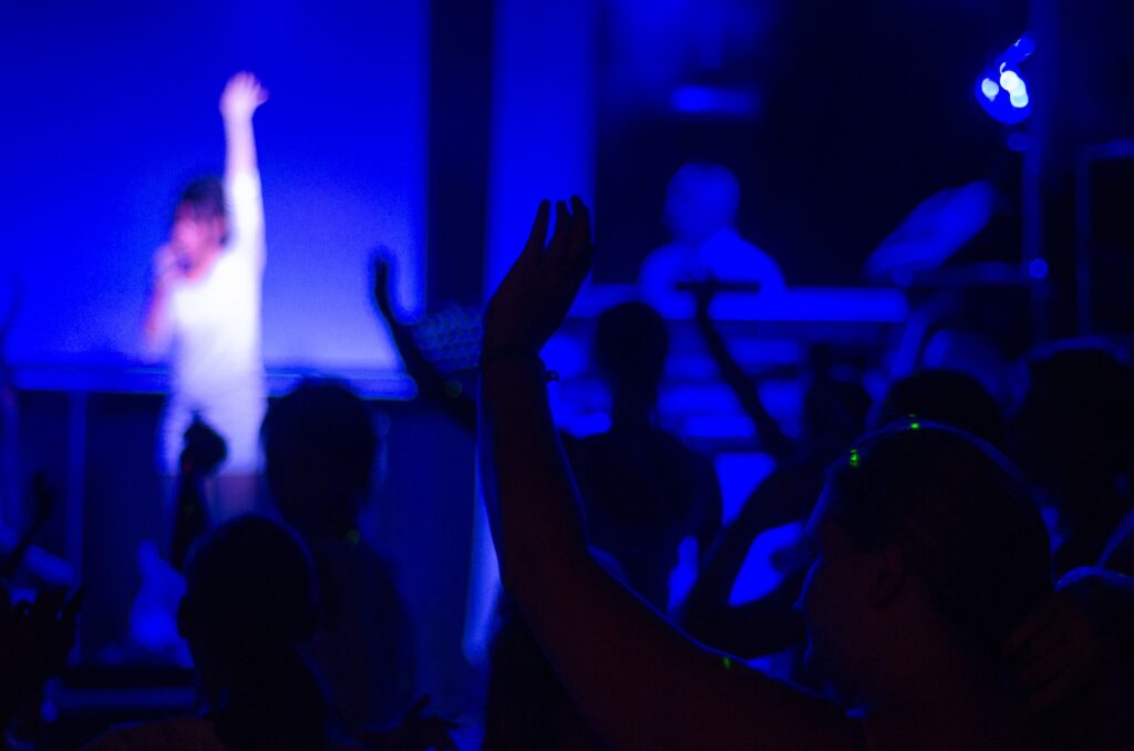 ステージで手を挙げて歌っている女性と観客