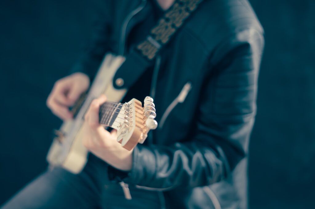 黒いジャケットを着てギターを弾いている人